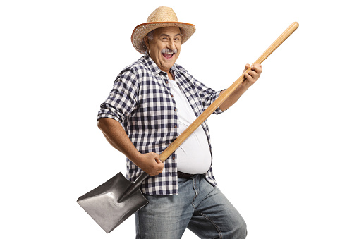 Mature farmer dancing with a shovel isolated on white background