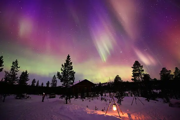 Night sky with Aurora Borealis and the Pleiades above country house.