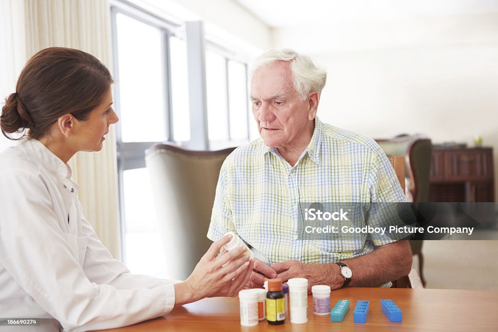 Take two tablets a day A young caregiver talking with her patient about his medication 40-49 Years Stock Photo
