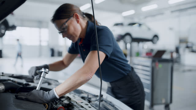 SLO MO Female mechanic fixing car engine in auto repair shop