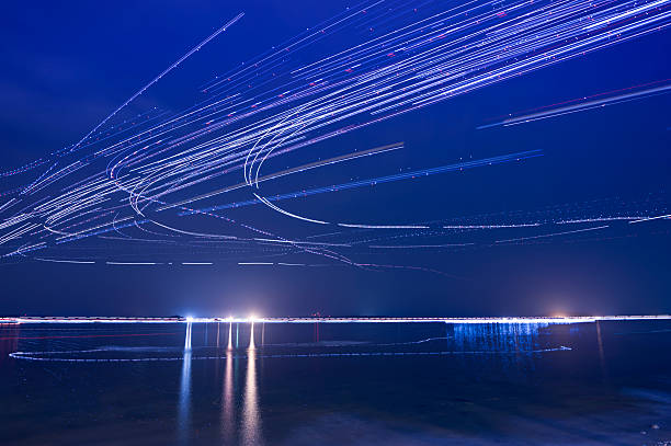 Light trails of Airplanes Light trails of airplanes taken off from airport nearby during the night, sea as foreground. long exposure stock pictures, royalty-free photos & images