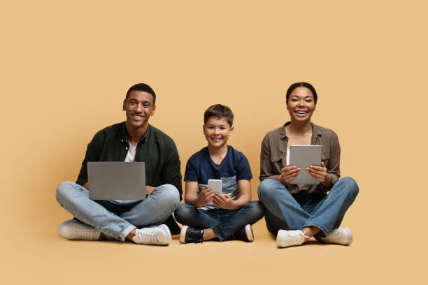 istock Young black family of three holding using different electronic devices 1866925355