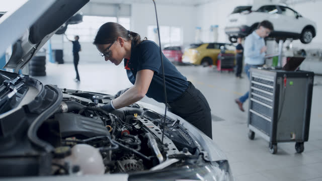 Female mechanic repairing car engine in auto repair shop