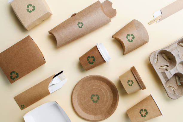 istock Disposable tableware made from biodegradable paper with recycling signs on a yellow background. View from above. 1866951416