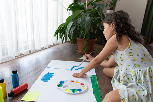Little girl artist paints in his studio
