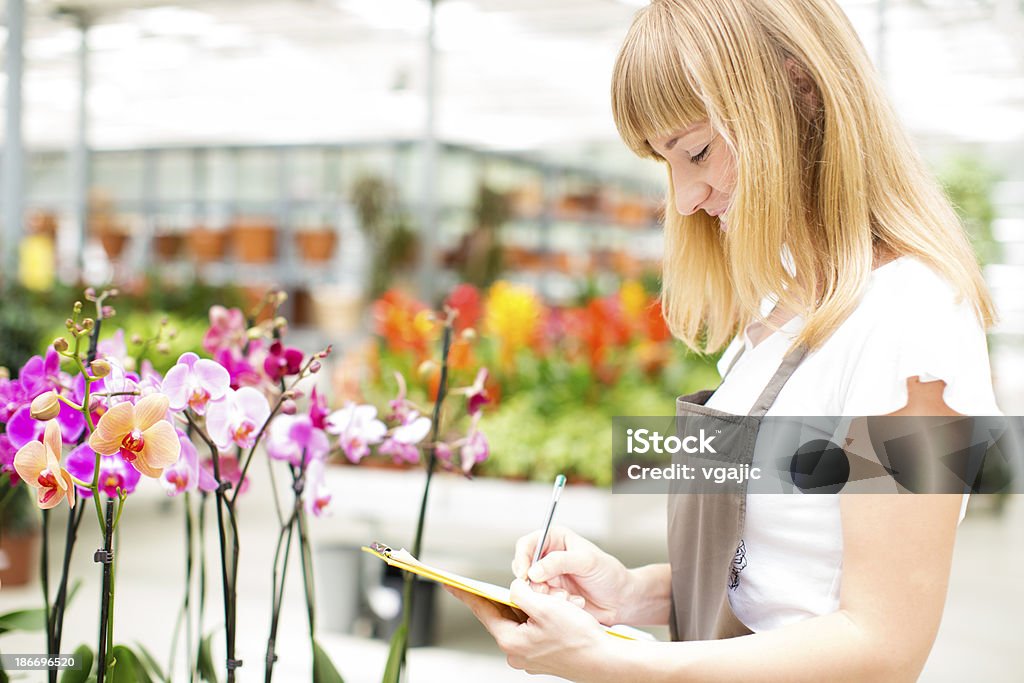Fiorista femmina lavorando in giardino centro. - Foto stock royalty-free di 25-29 anni