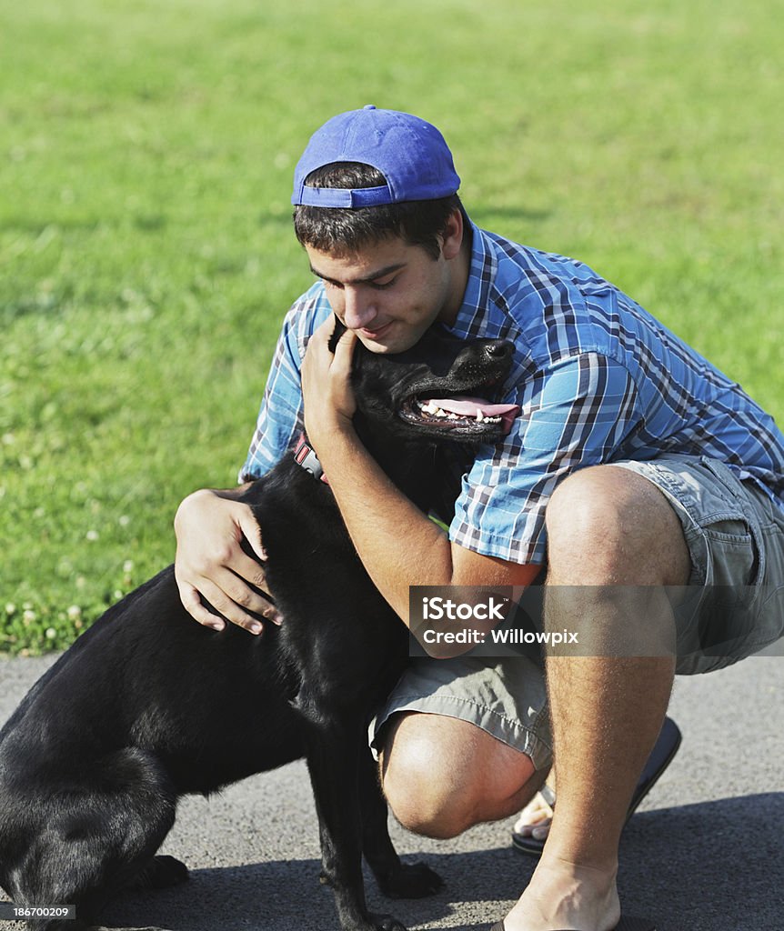 Cariñoso joven, que abrazan Labrador negro - Foto de stock de Abrazar libre de derechos