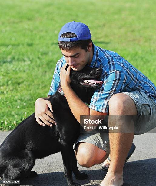 Cariñoso Joven Que Abrazan Labrador Negro Foto de stock y más banco de imágenes de Abrazar - Abrazar, Adulto, Adulto joven
