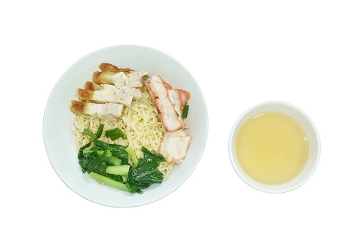 dry Chinese yellow egg noodles topping slice crispy and barbecue pork with cabbage on bowl eat couple clear soup