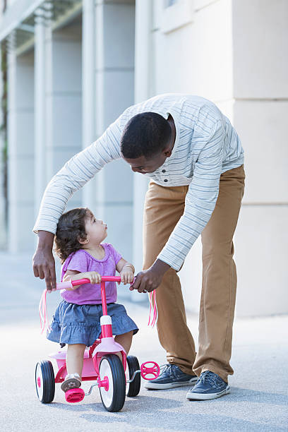 istock Father helping toddler ride tricycle 186702009