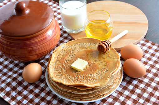 pancakes on the plate with eggs, glass of milk and honey