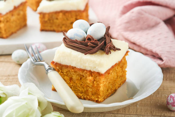 istock Easter carrot cake bars decorated with chocolate nest and chocolate candy eggs blossoming cherry or apple flowers on rustic light wooden backgrounds. Easter holiday meal. Traditional Easter food. 1867031987