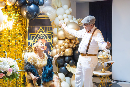 A couple in 1920s attire shares a joyful dance at a glittering Gatsby-themed birthday party.