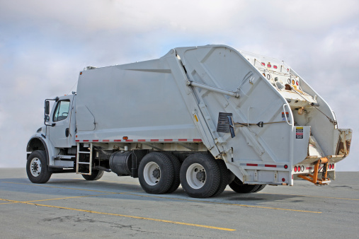 Rear quarter view of a waste management vehicle, aka garbage truck.