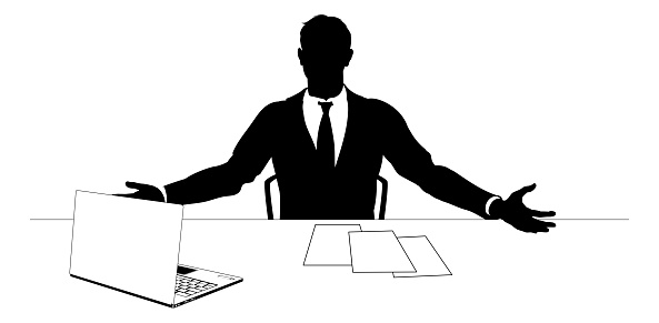Man in silhouette wearing a business suit at a desk with laptop and paperwork