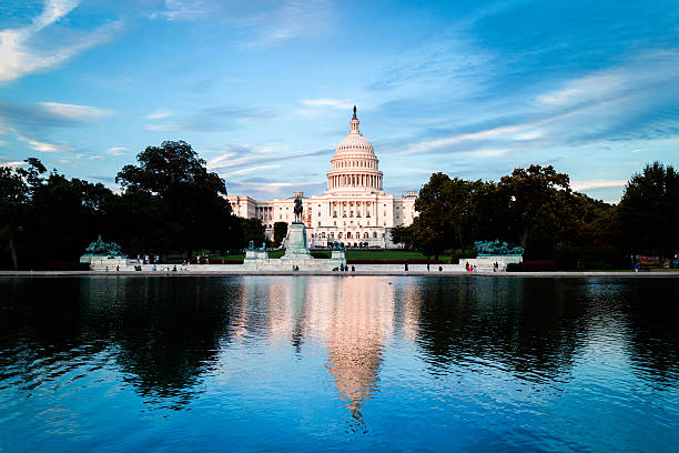 US Capitol building reflecting in water with blue sky stock photo