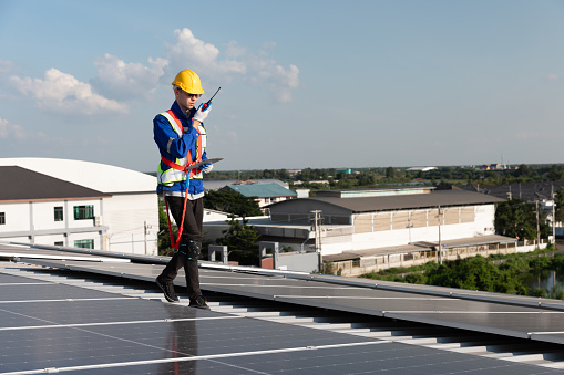 Engineer using walkie talkie during check solar panel on the rooftop