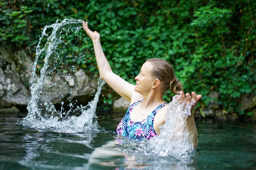 Cheerful senior women splashing and jumping in in hot thermal water near Smarjeske toplice - spa, Slovenia. Europe.