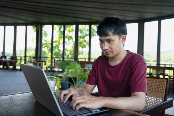 istock young asian man working remotely on internet online over laptop on vacation,take a break in cafe on the mountain, destination in Thailand 1867114268