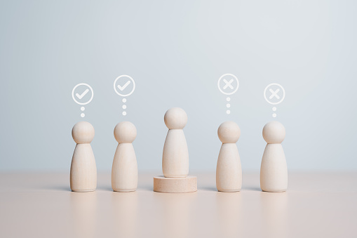 Wooden figures peg dolls stand above wooden circle among others with vote yes or no symbol. Open-mindedness or public hearing, volunteers, candidates, constituency electorates, and elections concept.