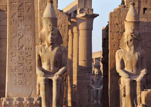 The first light of dawn casts shadows and illuminates the faces of Pharaoh's, hieroglyphics and pillars of the Ancient Egyptian temple at Luxor (1400 BCE)