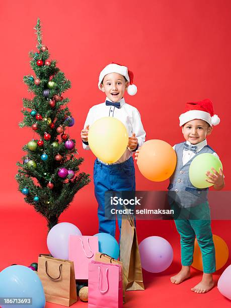 Photo libre de droit de Petits Frères Avec Chapeau De Père Noël Sur Fond Rouge banque d'images et plus d'images libres de droit de Cadeau de Noël