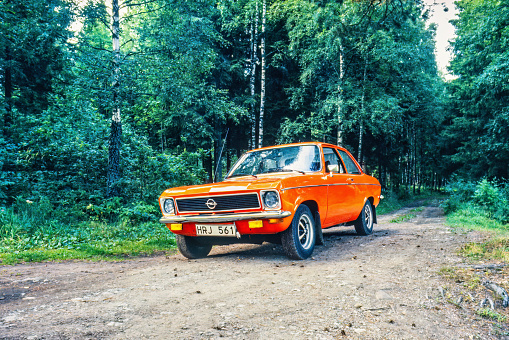 Falköping, Sweden-July 1982: Orange Opel Ascona a 1973 model year on a road in the forest
