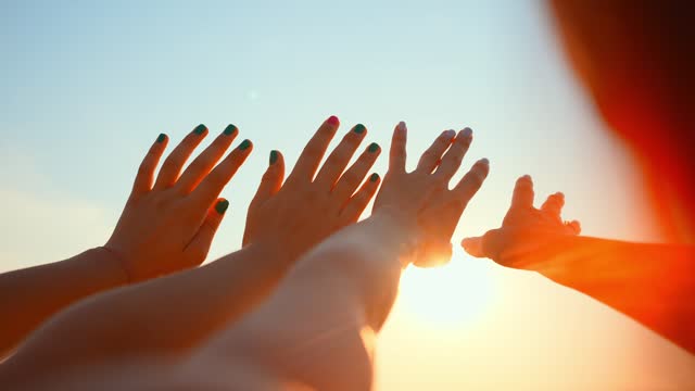 Close up many female hands raised up against blue sky. Friendly team. Gestures, symbols and signs. Participation in public vote. Swing arms to beat of music in dance. Sunny summer outdoor nature.