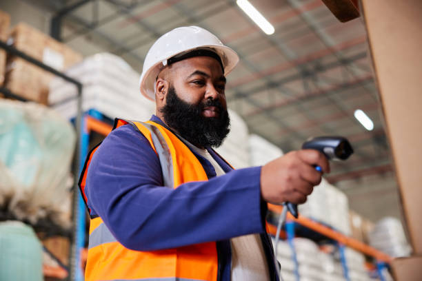 worker scanning boxes with a bar code reader in a large shipping warehouse - bar code reader bar code reading laser imagens e fotografias de stock