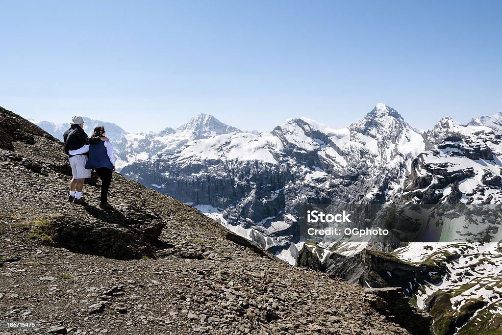 couple d'âge mûr en admirant une chaîne de montagnes recouvertes de neige - Photo de Activité de loisirs libre de droits