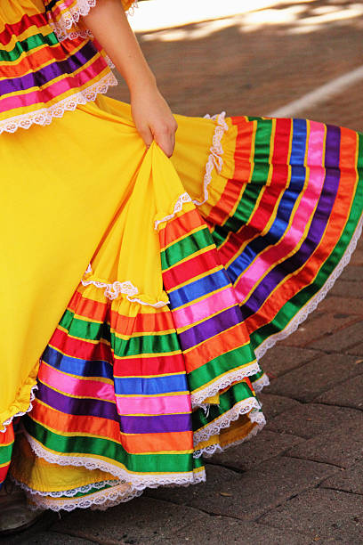 A section of a Mexican dresser's dress during a Mexican celebration. Like all folk dancing, traditional Mexican dances provide a glimpse into the culture of the region. Not only do these dances from Mexico express the rhythms of the music, but also the vital colors woven into Mexican clothing and decoration.