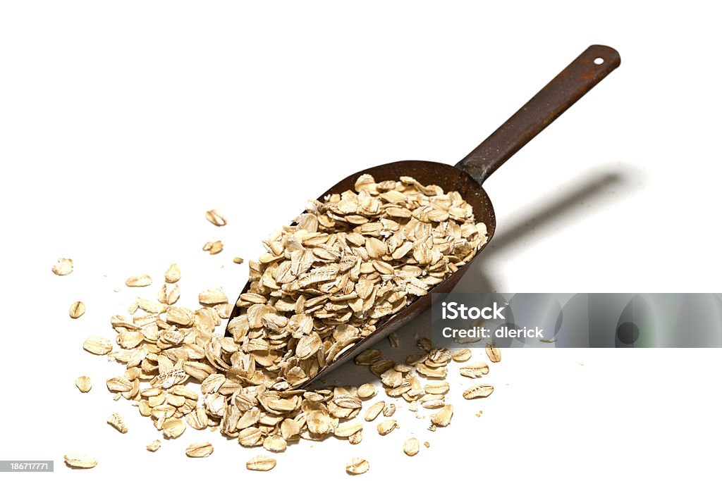 scoop of oats keep the doctors away Rolled oats in metal scoop isolated on white. Rolled Oats Stock Photo