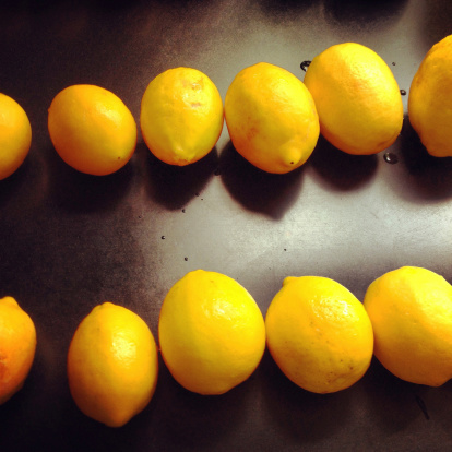 Two rows of Meyer lemons against a black granite countertop, with water droplets.  Taken with an iPhone and processed in Instagram.