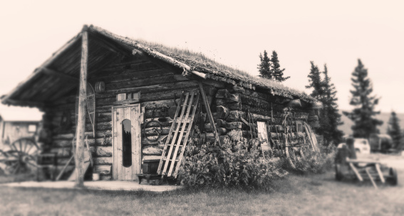 Antique cabin of Klondike Gold Rush period, Eagle town close of Fairbanks, Alaska. Toned monochrome image with aged effect.