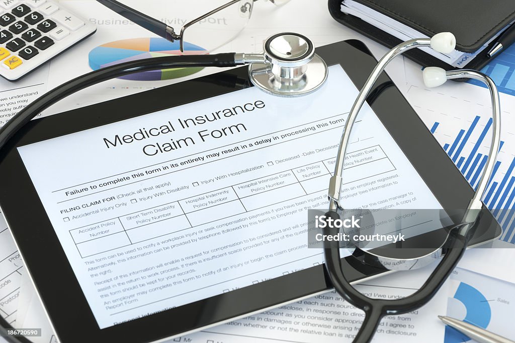 Medical insurance claim form on a digital tablet Medical insurance claim form on a digital tablet with paperwork Healthcare And Medicine Stock Photo