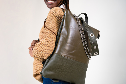 Unrecognizable young female fashion model Black ethnicity, carrying an leather backpack