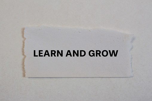 Learn and grow lettering on ripped paper. Conceptual photo.