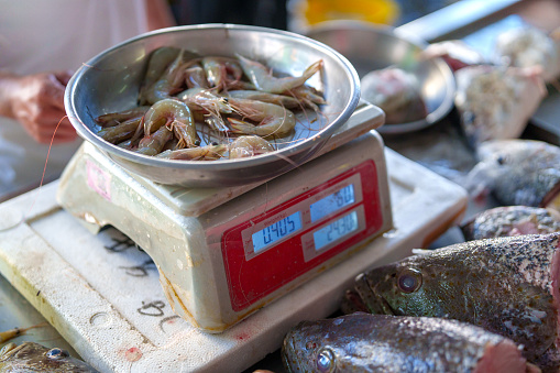 The scales used for measuring and weighing various items sold at the market. It provides a glimpse into the traditional market setting and the tools commonly used by vendors for their trade.