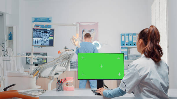 istock Dentist using green screen on monitor and talking to man assistant 1867230549