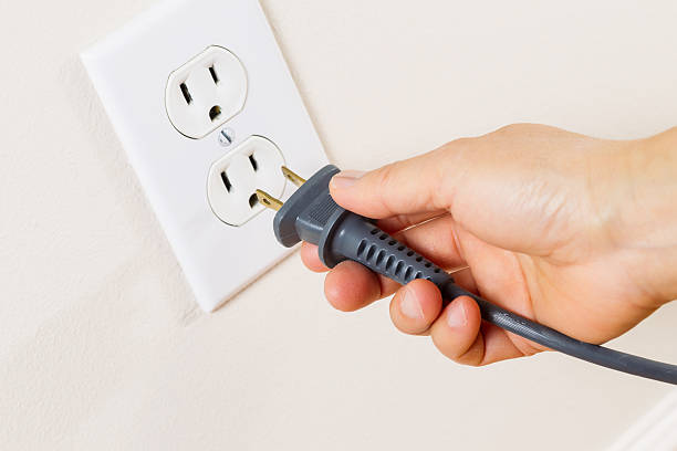 inserting power cord receptacle in wall outlet - huishoudelijk apparaat fotos stockfoto's en -beelden
