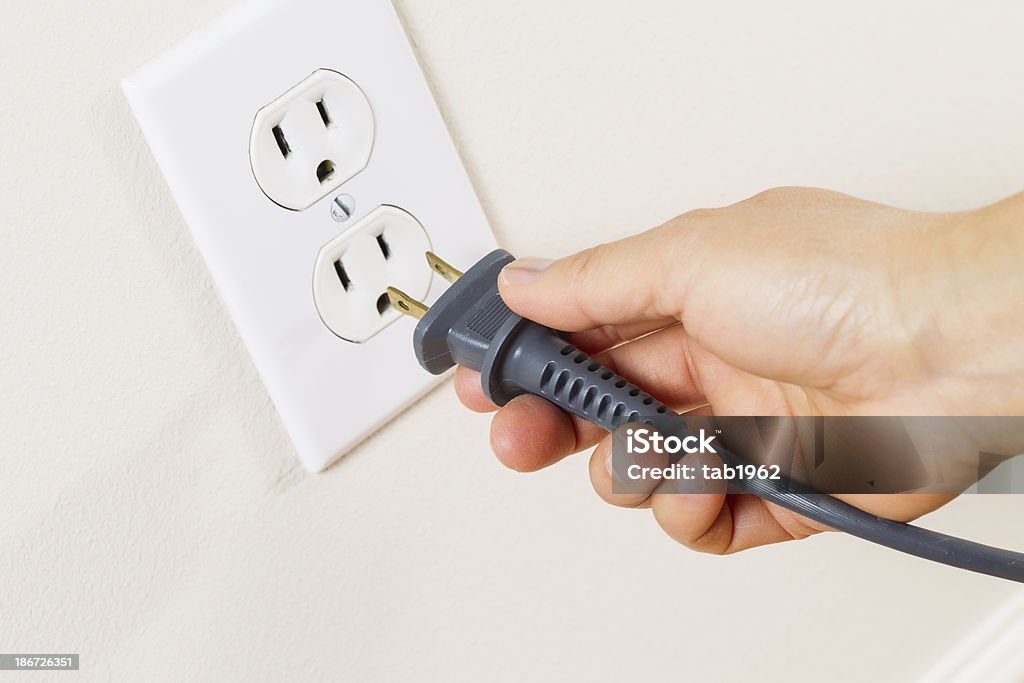 Inserting Power Cord Receptacle in wall outlet Horizontal photo of female hand inserting power cord receptacle into electric wall outlet Electric Plug Stock Photo