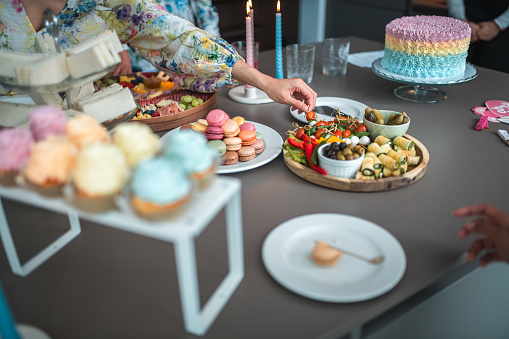 A variety of colorful French macarons displayed next to elegant sandwich triangles, part of a diverse and delicious party buffet spread.