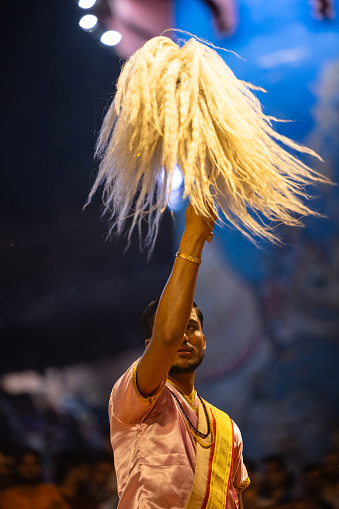 Varanasi, Uttar Pradesh, India - March 2023: Ganga aarti, portrait of hindu male priest performing holy river ganges evening aarti at dashashwamedh ghat in traditional dress with rituals.