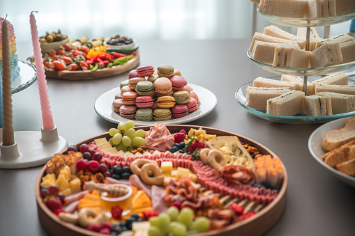 An elegant tower of colorful French macarons takes center stage among the baby shower feast, offering a taste of sophistication.