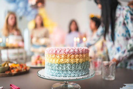 Beautiful colorful and delicious cake at a baby shower celebration displayed on a tray with diverse females in the background.