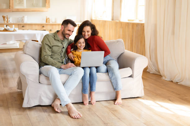 istock Parents and daughter girl using laptop computer together at home 1867282528