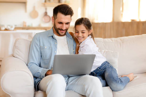 istock Cheerful daddy and daughter having fun with laptop at home 1867283051