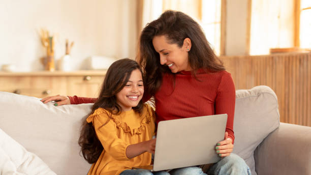 istock Joyful Eastern Mom And Daughter Using Laptop At Living Room 1867283090