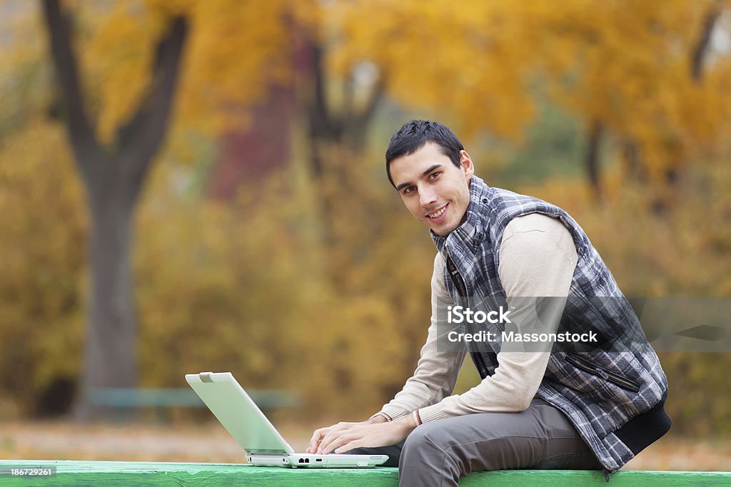 Programmer with notebook sitting in autumn park Adult Stock Photo