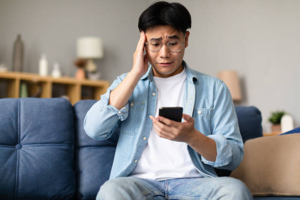 istock Shocked korean man having issue texting on smartphone at home 1867301033
